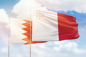 Sunny blue sky and flags of malta and bahrain