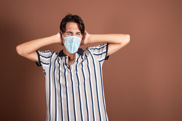 Emotional young man in a medical mask on a brown background. Medicine and diseases by airborne...