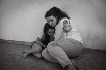 Black and white portrait of abused family. Young scared mother woman holding daughter girl,...