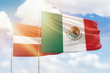 Sunny blue sky and flags of mexico and latvia