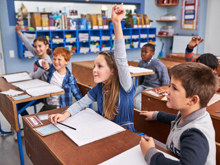 All eager to answer the question. Cropped shot of elementary school children in class.