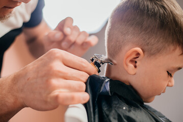 Boy haircut by master hairdresser with machine
