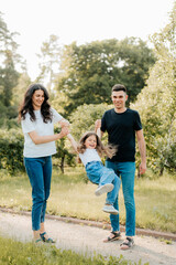 Fototapeta premium Mom dad and daughter on a walk in the park