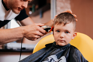 Boy haircut by master hairdresser with machine