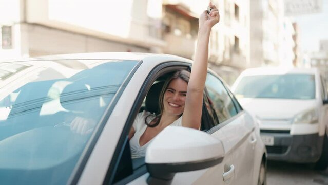 Young woman smiling confident holding key of new car at street