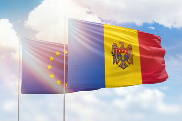 Sunny blue sky and flags of moldova and european union