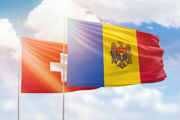Sunny blue sky and flags of moldova and switzerland