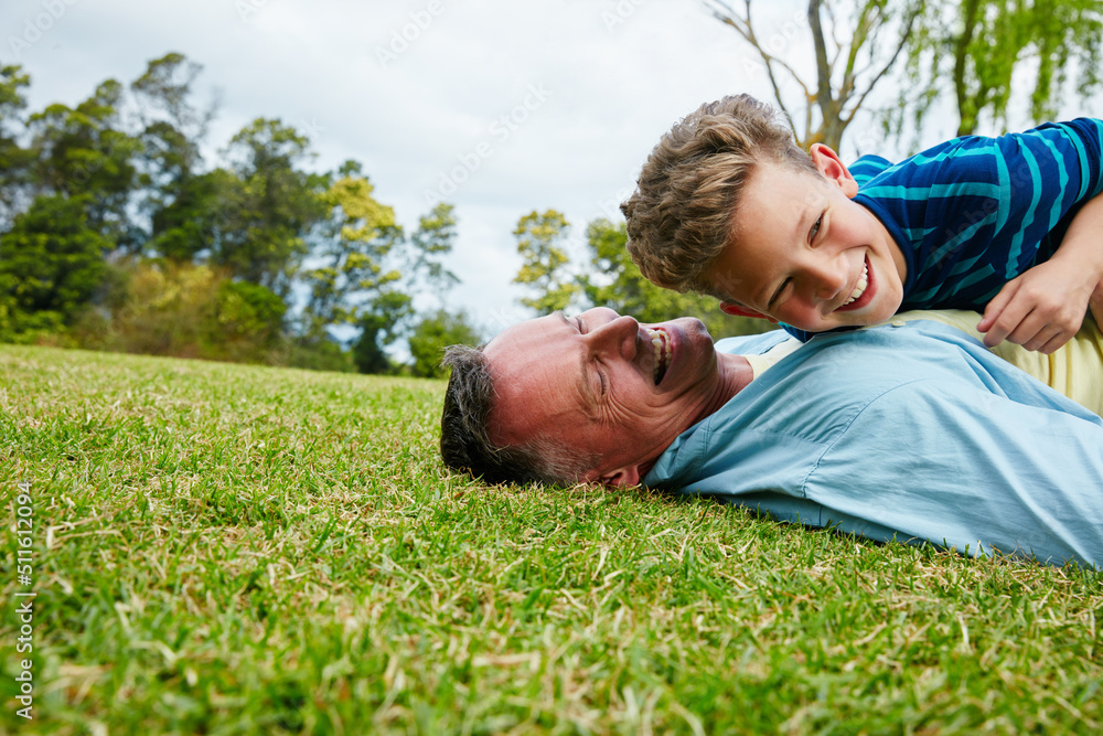 Poster Sharing moments between father and son. Shot of a laughing father and son lying on grass.