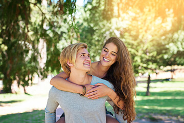Naklejka premium Where to next, my lady. Shot of a happy young couple enjoying a piggyback ride outdoors.
