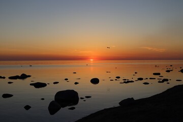Sunset over calm Baltic sea, in Saulkrasti, Latvia. Sun shining from behind clouds, bright...