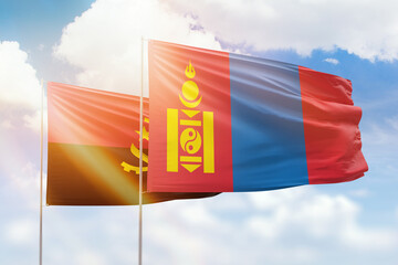 Sunny blue sky and flags of mongolia and angola
