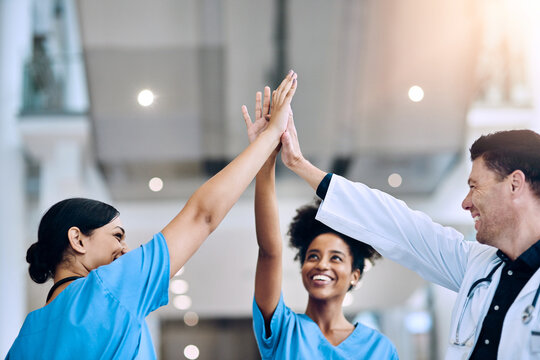 We did it together. Shot of a diverse team of doctors giving each other a high five in a hospital.