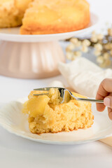 Moist and delicious homemade pineapple cake. Cake being cut. Slice of cake placed on a plate, ready to eat. Person cutting piece of cake to eat. White background.