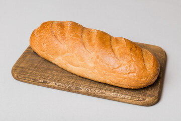 Freshly baked bread on cutting board against white wooden background. perspective view bread with copy space