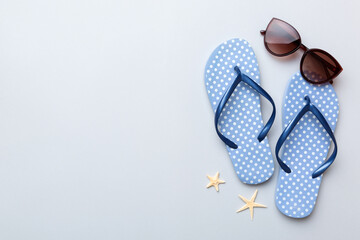 Summer travel concept. Flip flops, sunglasses and starfish on white. Top view on colored background