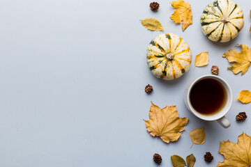Flat lay composition with colorful Autumn cup of coffee and leaves on a color background. top view
