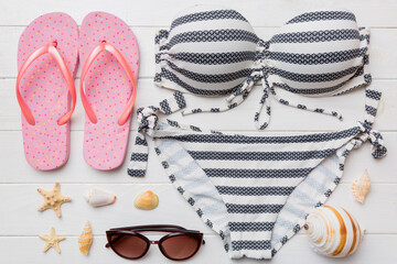 Woman swimwear and beach accessories flat lay top view on colored background Summer travel concept. bikini swimsuit, straw hat and seasheels. Copy space Top view