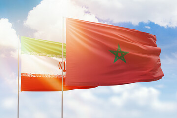 Sunny blue sky and flags of morocco and iran