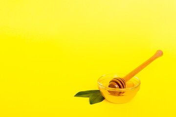 Fototapeta premium Honey in jar with leaves and honey dipper on colored background top view with copy text