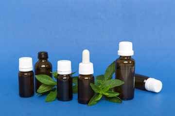 Natural Mint Essential Oil in a Glass Bottle. organic cosmetics with herbal extracts of mint on colored background