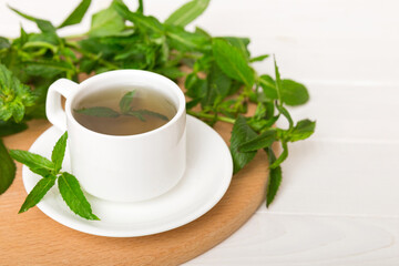 Cup of mint tea on table background. Green tea with fresh mint top view with copy space