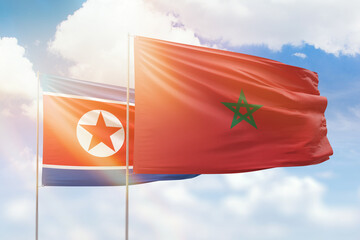 Sunny blue sky and flags of morocco and north korea