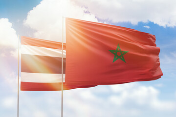 Sunny blue sky and flags of morocco and thailand