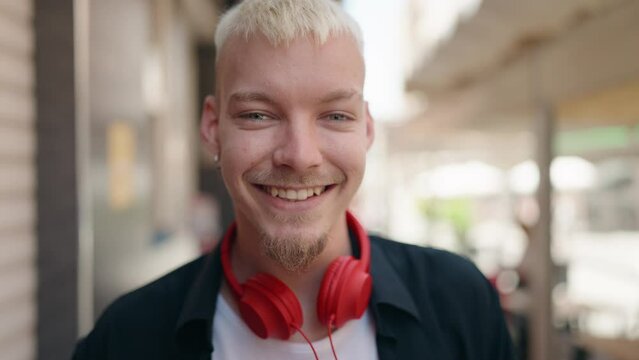 Young caucasian man smiling confident wearing headphones at street