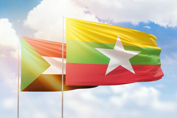 Sunny blue sky and flags of myanmar and sudan