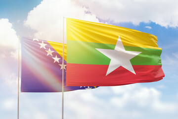 Sunny blue sky and flags of myanmar and bosnia