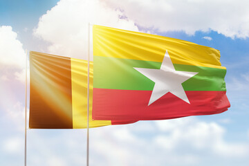 Sunny blue sky and flags of myanmar and belgium