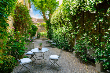 An empty, secluded cafe patio garden in the medieval village of Saint-Remy-de-Provence, in the...