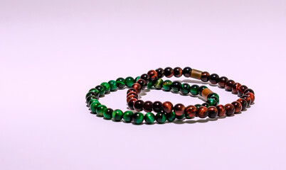 Two beautiful bracelets of green and brown on a purple background. 