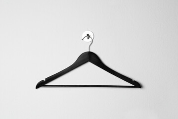 Empty black clothes hanger on white wall