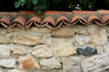 Old stone wall with red roof tiles outdoors