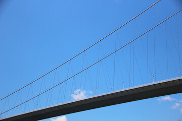 Close view of a bridge seen from below with a clear sky with a small cloud in the background