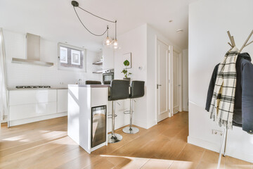 The interior of a modern apartment with a kitchen and bar with a dining area in white on a parquet...
