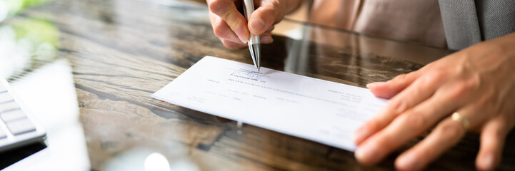 Businessperson's Hand Signing Cheque