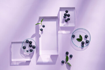 Top view of blueberry extract with transparent podium and blank space in purple background 