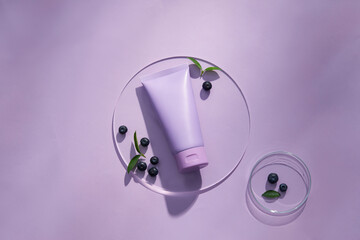 Top view of blueberry extract with transparent podium and cosmetic jar in purple background 