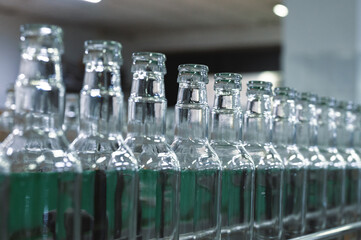 Conveyor belt carries clean glass bottles for alcohol drinks