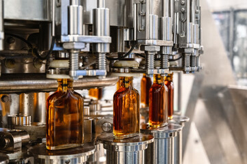 Conveyor carries glass bottles of luxury cognac in workshop