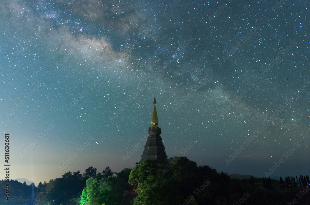 Wall mural the milky way galaxy over a sacred temple at doi inthanon national park, chiang mai, thailand. starr