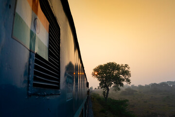 A train running towards horizon where sun is rising, orange sky of a new dawn in the background. Indian railway stock Image,
