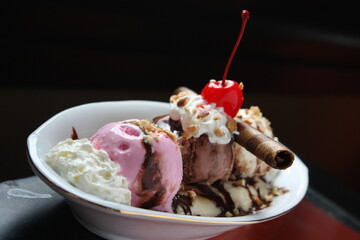 Banana split ice cream on wood table. Homemade Banana Split Sundae with Chocolate Vanilla. Topped with mashed peanuts and cherries