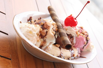 Banana split ice cream on wood table. Homemade banana split sundae with chocolate, vanilla ice cream.