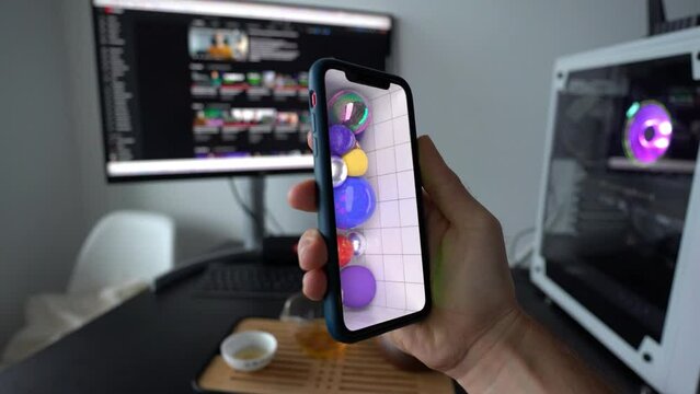 Montreal, Canada, May 12, 2022: Close up of man playing with 3D NFT art on his phone near computer. NFT concept. 3D Animation. VR and AR.