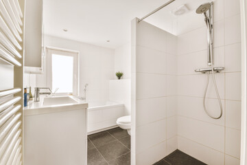Modern flush toilet and ceramic sink installed on white tiled walls near mirror and towel in small...