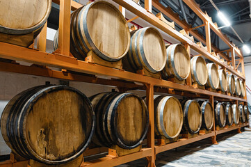 Wooden casks full of hard alcohol drinks stand on large rack