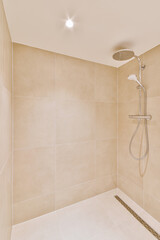 Shower faucets attached to tiled wall near glass partition and ornamental curtail in washroom at...